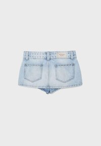 Mini-jupe en jean bleu clair avec des ornements cloutés sur la ceinture et les poches arrière, avec une étiquette sur le côté droit de la ceinture.