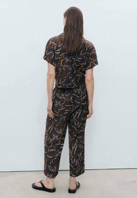 Brown patterned shirt and pants set, featuring floral designs in blue and white, made from lightweight fabric, with a relaxed fit and short sleeves.