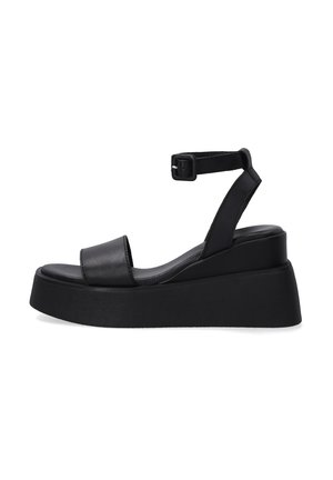 Sandalias de plataforma de cuero negro con correa en el tobillo, que presentan una amplia correa en la parte de los dedos y una suela de cuña texturizada.