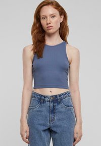 Modra rebrasta kratka majica s okroglim izrezom, v kombinaciji z visokim pasom in svetlim teksasom. Ima gladko teksturo in sproščen kroj.