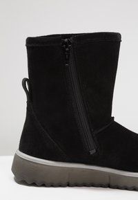 Stivale alla caviglia in suede nero con cerniera laterale, parte superiore testurizzata e suola grigia robusta con battistrada pronunciato per una maggiore aderenza.