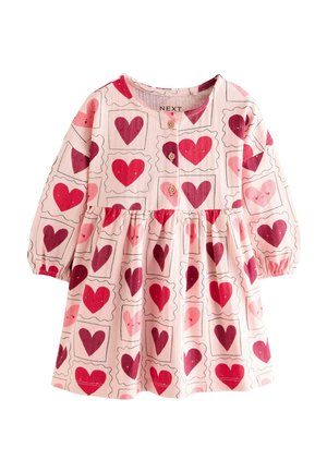 Long-sleeve pink dress featuring heart print in various shades of red, with a gathered skirt and button closure at the neckline.