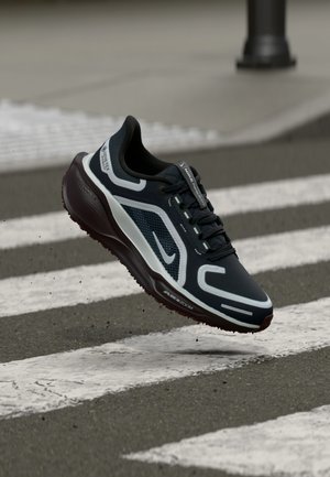 Zapatilla de running Nike con parte superior de malla azul marino oscuro, detalles en blanco, suela de goma, amortiguación Air Zoom y un diseño texturizado y flexible.