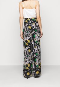 Breda byxor i svart tyg med ett blommönster i gult, vitt och grönt. Har en bekväm midja och en flödande design.