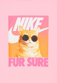 Oranžs tabby kaķis ar apaļām melnām saulesbrillēm priekšā rozā un oranžā Nike logotipa ar tekstu "FUR SURE" zem tā.