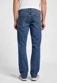 Jeans de denim azul con un diseño de pierna recta, que cuentan con dos bolsillos traseros, costuras en contraste y una etiqueta de cuero en la cinturilla.
