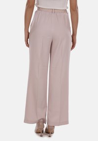 Pantaloni ampi rosa chiaro con vita elasticizzata, texture liscia e vestibilità sartoriale, che terminano appena sopra la caviglia.
