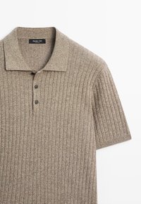 Beige ribbed knit polo shirt with short sleeves and two-button placket, made of soft textured fabric.