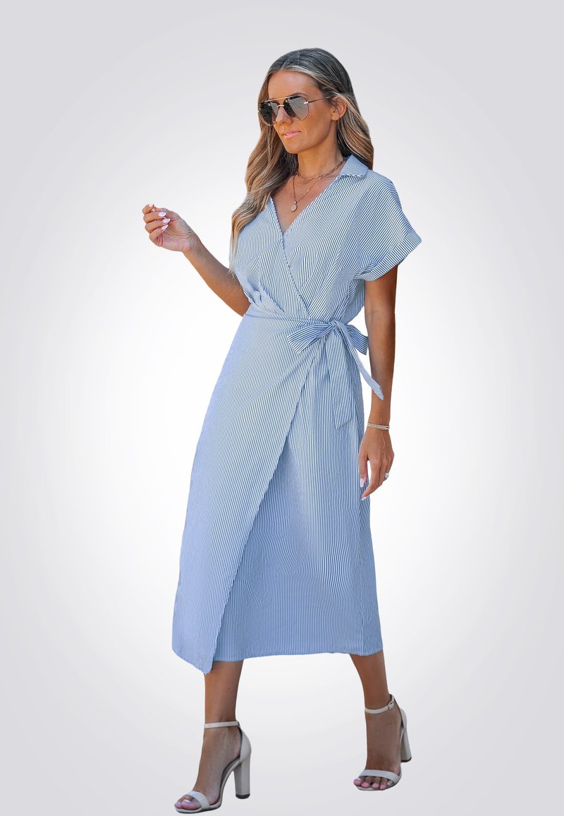 Vestido envolvente de rayas azul claro con mangas cortas, cintura ceñida y un diseño de longitud media. Lleva sandalias de tacón alto plateadas.