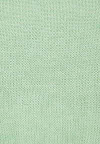 Tessuto lavorato a maglia verde chiaro con una trama fine e testurizzata, caratterizzato da un motivo uniforme e un aspetto morbido. Adatto per varie applicazioni tessili.