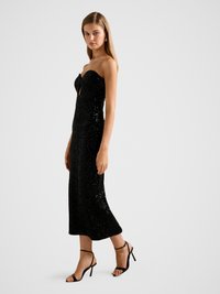 Zwart pailletten strapless jurk met een nauwsluitende pasvorm, knie-lengte en een sleutelgatdetail bij de buste, gecombineerd met zwarte sandalen met bandjes.