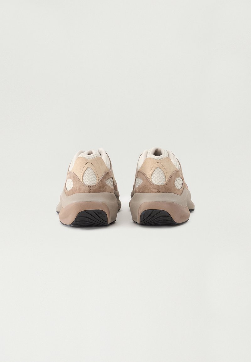 Scarpe da ginnastica beige e taupe realizzate in materiali in rete e scamosciati, design arrotondato, suole imbottite e suole esterne in gomma testurizzata.