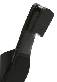 Gros plan de la semelle d'une chaussure à talon haut noire avec un talon bloc carré brillant et une semelle à texture antidérapante.
