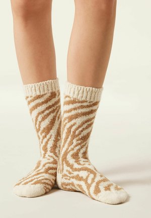 Chaussettes rayées marron et crème, fabriquées en matériau doux et pelucheux, avec une bordure côtelée et un design confortable arrivant mi-mollet.
