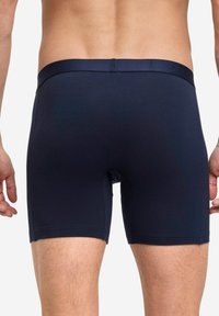 Boxer in blu navy con una texture liscia, vita elasticizzata con logo del marchio e taglio a metà coscia, progettati per comfort e vestibilità.