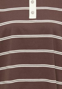 Pruun triibuline polo särk, millel on valged horisontaalsed triibud, nööpidega kaunistatud nööbiliist kahe dekoratiivse nupuga ning pehme puuvillane tekstuur.