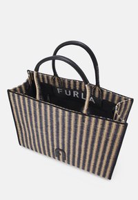 Striped tote bag in navy and beige woven material with black leather accents. Features two handles and a decorative logo on the front.