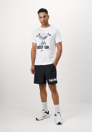 White cotton t-shirt with a black graphic and text "BEEF UP." Black athletic shorts with white "NIKE" logo. White sneakers with red accents.