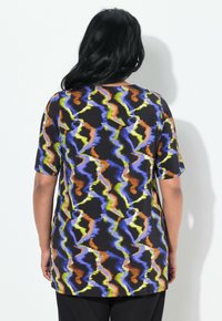 Chemise noire avec un motif en zigzag coloré en bleu, orange, jaune et vert. Manches courtes, col rond et coupe décontractée.