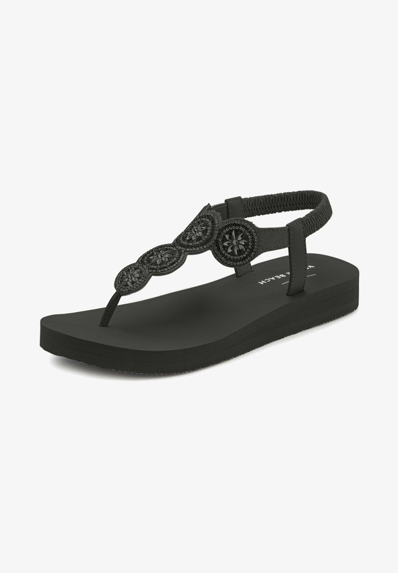 Schwarze Flip-Flop-Sandale mit flacher Sohle, ausgestattet mit einem strukturierten Riemen, der mit kreisförmigen Akzenten und floralem Muster verziert ist. Hergestellt aus Gummi.