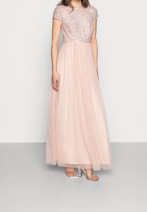 Ljusrosa kvällsklänning med en paljetterad bodice och tylskjol, med rundad halsringning och korta ärmar. Genomskinliga högklackade sandaler.