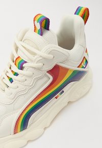 Fehér sneaker hálós és bőrből, szivárványcsíkos dizájnnal és színes címkével. Kerek gumitalp, textúrázott részletek.