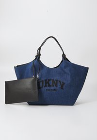 Sininen farkkukassi mustilla nahkaosilla ja -kahvoilla. Varustettu rohkealla mustalla "DKNY NEW YORK" tekstillä. Mukana irrotettava musta vetoketjullinen pussukka.