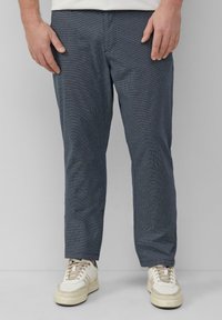 Marineblauwe geruite broek gemaakt van lichtgewicht stof, met een ontspannen pasvorm en een recht gesneden ontwerp. Gecombineerd met witte sneakers en een simpele witte shirt.