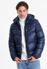Granatowa kurtka puchowa z kapturem, z poziomymi pikowanymi panelami, dwoma zapinanymi na zamek kieszeniami na klatce piersiowej oraz gładką, błyszczącą powierzchnią.