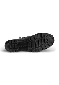Suela de zapato de goma negra con un patrón de banda de rodadura que presenta secciones elevadas para agarre, incluyendo formas circulares y rectangulares.