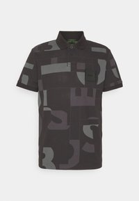 Polo noir avec des motifs géométriques en gris foncé. Il comporte un col, deux boutons et une poche avant avec une étiquette noire.