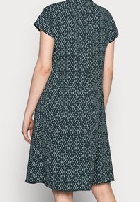 Krátkozávěsné šaty z tmavozelené látky s bílým vertikálním vzorem, nabízející volný střih a jednoduchý kulatý výstřih.