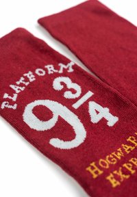Calzini rossi con scritte bianche che riportano "PLATFORM 9¾" e "HOGWARTS EXPRESS" in giallo. Tessuto morbido a maglia, lunghezza medi-calf, design casual.