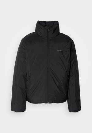 Zwarte pufferjack met een hoge kraag, rits aan de voorkant en zijzakken. Gladde, glanzende textuur met een minimalistisch logo op de borst.