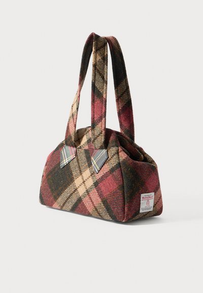 Vilnas soma rūtainā rakstā sarkanā, bēšā un zaļā tonī. Tai ir apaļa forma, īsas rokturi un uz sāniem ielikta logotipa uzšuve.