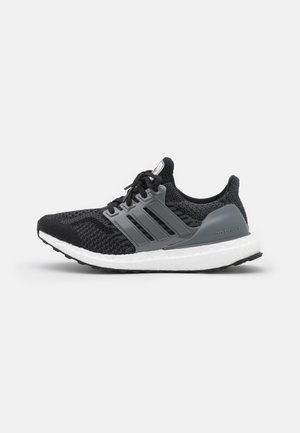 Black and gray Adidas Ultra Boost running shoe with white cushioned sole and black laces, displayed against a plain background.