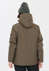 Brun, vattentät jacka med huva, med en slät textur och en enda axelpatch som accent; bärs med en grön mössa.