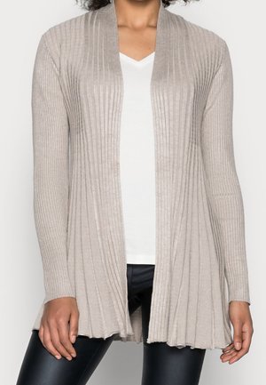 Beige gerippter Cardigan mit offenem Vorderteil, langen Ärmeln und strukturiertem Finish. Über einem weißen V-Ausschnitt-T-Shirt und schwarzen Leggings getragen.