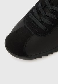 Mustad sportkinga, mis ühendab mati ja tekstuurse pinna, ümmarguse nina, polsterdatud keele ja lamedad paelad. Kummist tald, mis pakub haaret.