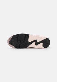 Nike sneaker zool gemaakt met een zwarte rubberen basis met textuur, voorzien van een gradatie van roze en crème kleuren en onderscheidende groefpatronen.