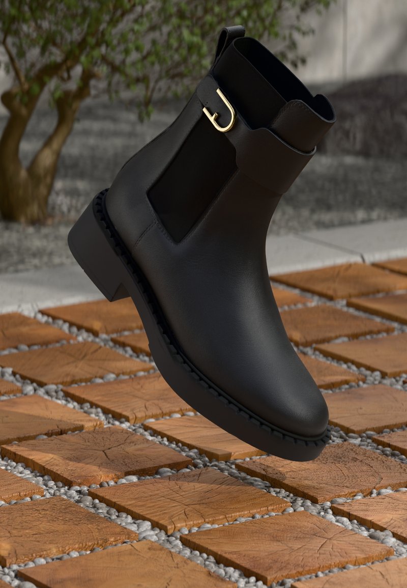 Stivaletto nero in pelle con pannelli laterali elastici e dettaglio della fibbia dorata, dotato di suola texture e un design elegante.
