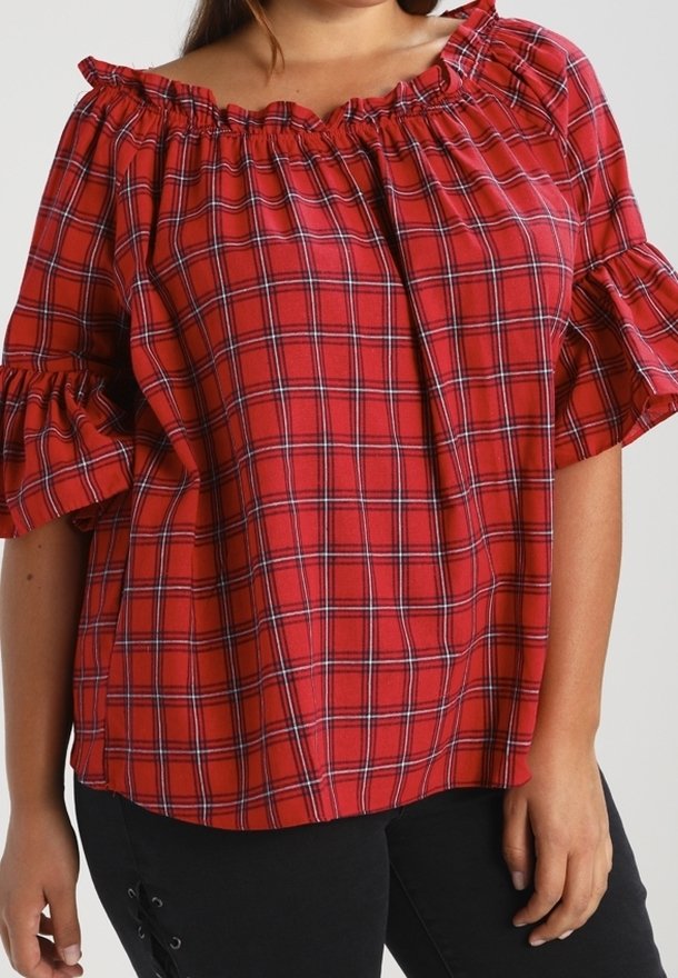 Blouse à carreaux rouges avec un col à volants dégageant les épaules et des manches courtes. Fabriquée en tissu léger avec une coupe ample.