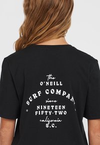 Must must shirt, mille valge tekstiga seljal, kus on kirjas "O'Neill Surf Company" ja asutamisaarv, lõdva lõikega ning lühikeste varrukatega.