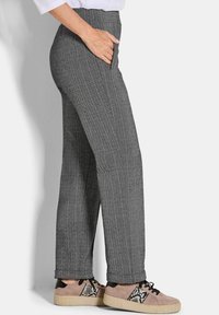 Grijze herringbone patroon broek met hoge taille en zijzak; gecombineerd met lichtbruine sneakers met een zwart-wit accent.