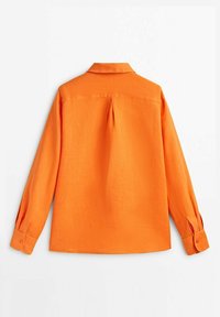 Chemise en lin orange à manches longues, col pointu, pli au dos et poignets à boutons. Texture lisse et design simple.