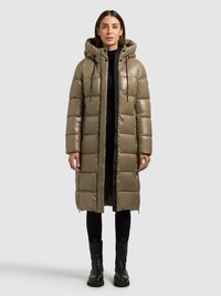 Abrigo acolchado color verde oliva con diseño de acolchado, capucha y cierre frontal con cremallera. Pantalones negros y botines completan el conjunto.