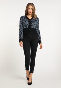 Blå og sort cardigan med leopardmønster, med v-hals, knaplukning og ribbet kant. Sættes sammen med sorte skinny jeans.