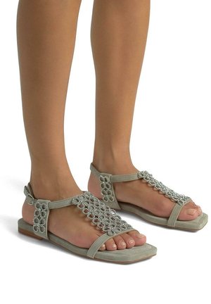 Sandales grises avec des accents décoratifs en perles argentées, design à bout ouvert et bride de cheville. Semelle plate avec une texture minimale et une silhouette épurée.