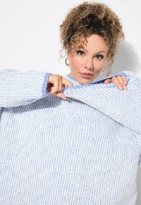 Maglione lavorato a maglia blu chiaro con strisce verticali, dotato di un collo alto e maniche ampie. La texture appare morbida e accogliente.