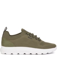 Sneaker verde oliva con tomaia in maglia, dettagli testurizzati e suola ondulata bianca. Presenta un'etichetta sul tallone e un design con lacci.